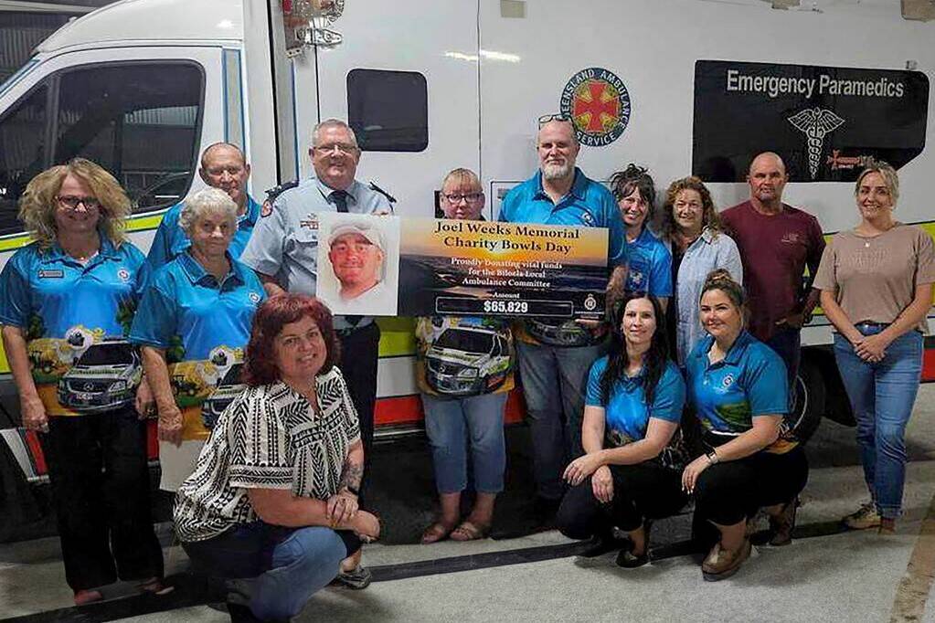 People standing in front of an ambulance with a charity cheque